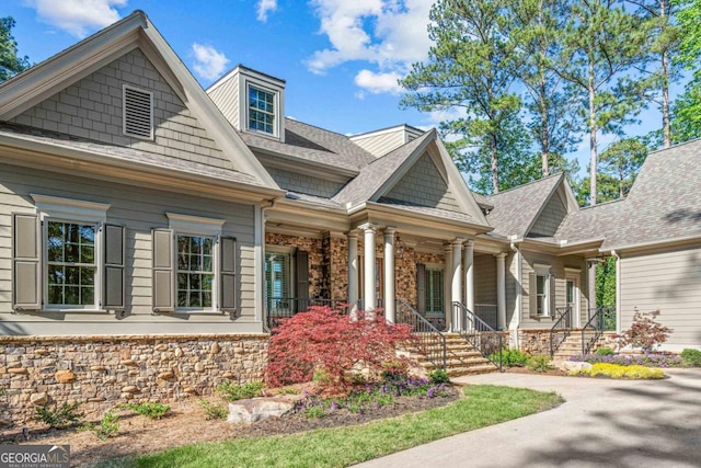 view of front of home with stone siding and roof with shingles