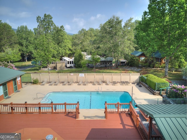 community pool featuring a patio area, fence, and a wooden deck