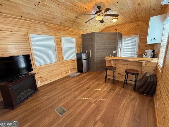 kitchen with a breakfast bar, visible vents, wood ceiling, vaulted ceiling, and freestanding refrigerator