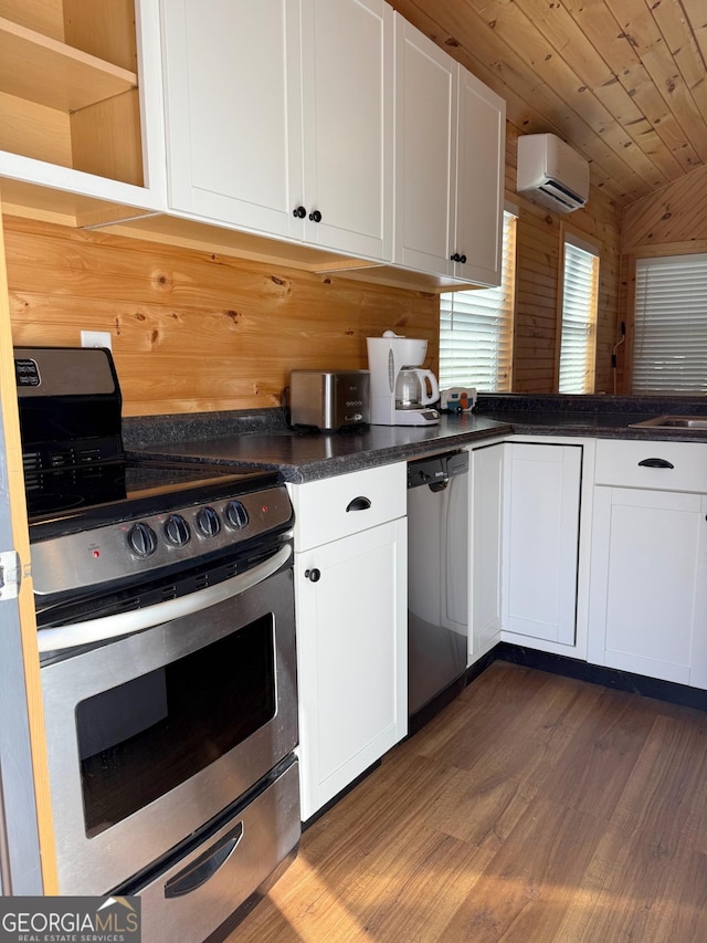 kitchen with white cabinets, dark countertops, stainless steel appliances, and an AC wall unit