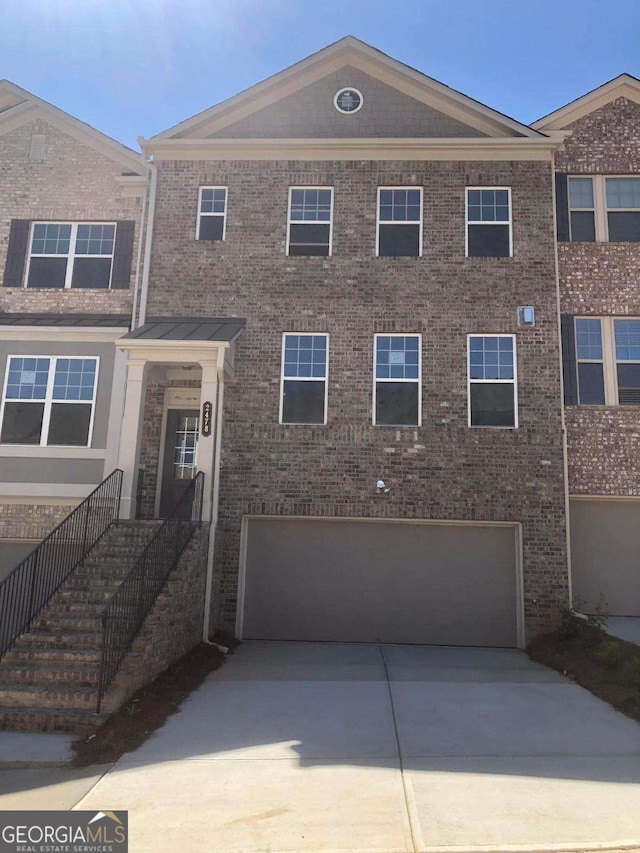 multi unit property featuring brick siding, driveway, and an attached garage