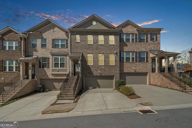 view of front of property featuring brick siding, an attached garage, stairs, and driveway