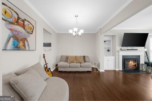 living room featuring built in features, ornamental molding, an inviting chandelier, wood finished floors, and a glass covered fireplace