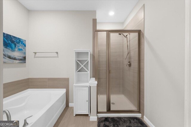bathroom featuring a stall shower, baseboards, and a garden tub
