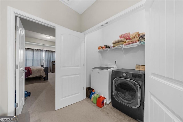 clothes washing area featuring washing machine and clothes dryer, laundry area, and light colored carpet