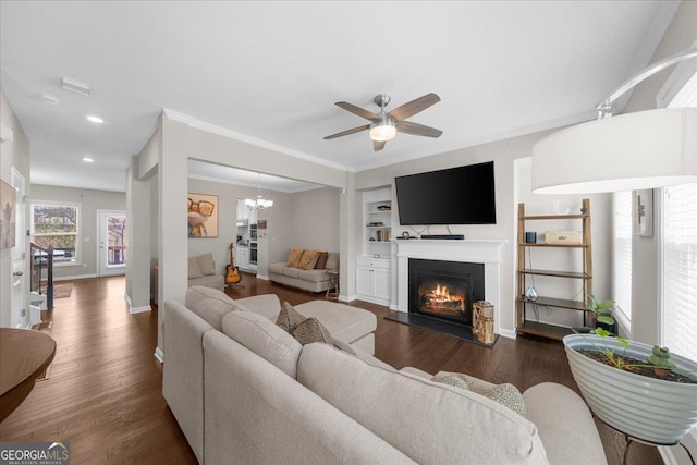 living room featuring ceiling fan, baseboards, a glass covered fireplace, and dark wood-style floors