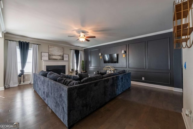 living room with ornamental molding, a fireplace, dark wood finished floors, and a decorative wall