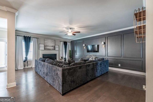 living room with ornamental molding, dark wood finished floors, a fireplace, and a decorative wall