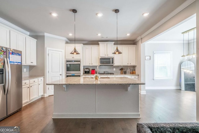 kitchen featuring hanging light fixtures, appliances with stainless steel finishes, an island with sink, and white cabinetry