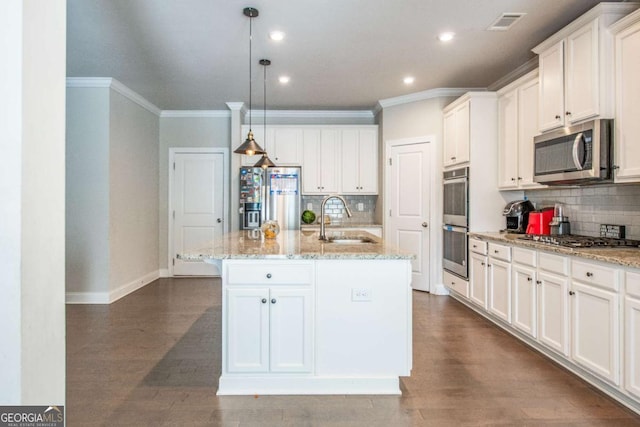 kitchen featuring pendant lighting, stainless steel appliances, white cabinetry, a sink, and an island with sink