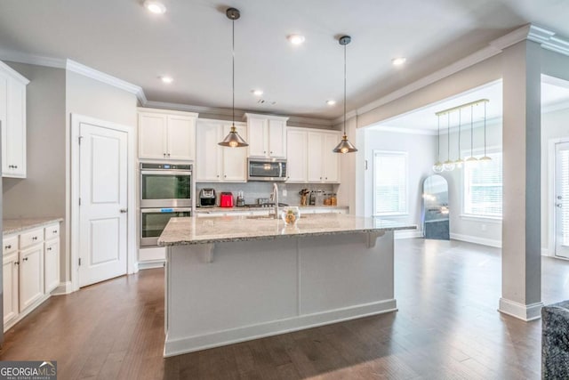 kitchen featuring decorative light fixtures, decorative backsplash, appliances with stainless steel finishes, a kitchen island with sink, and white cabinets