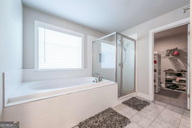 bathroom with a shower stall, a walk in closet, a bath, and tile patterned floors