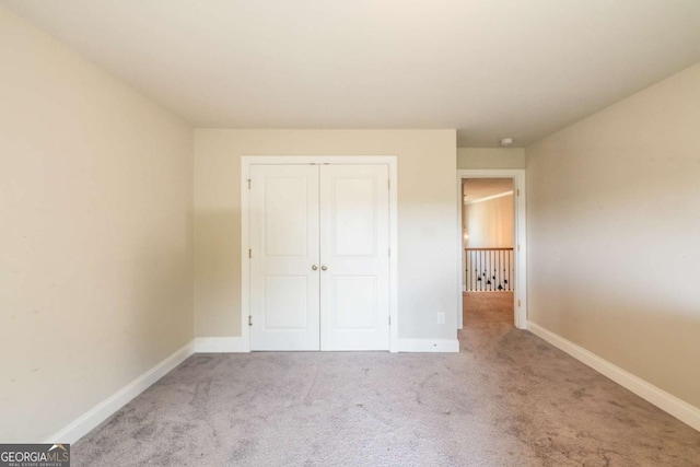 unfurnished bedroom featuring a closet, light colored carpet, and baseboards