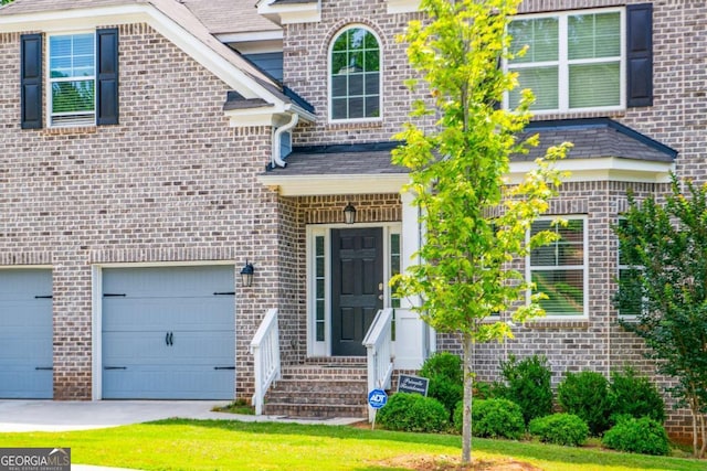 view of exterior entry featuring driveway and an attached garage