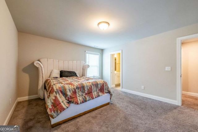 carpeted bedroom with ensuite bath and baseboards