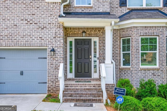 doorway to property with an attached garage and brick siding