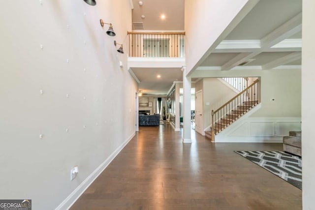 entryway with dark wood-style floors, a fireplace, visible vents, stairway, and a towering ceiling