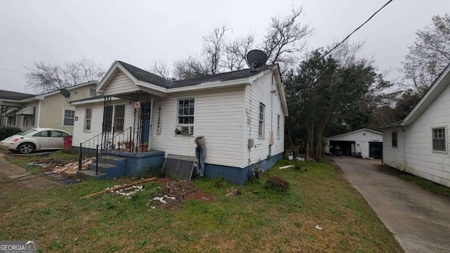 bungalow-style home with an outbuilding, a front lawn, and a detached garage