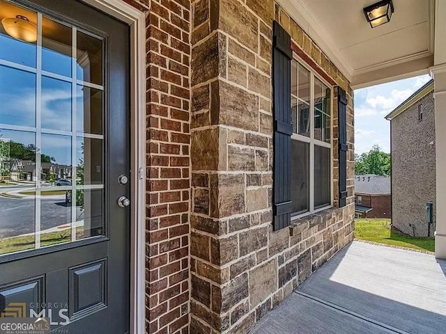 entrance to property with covered porch and brick siding