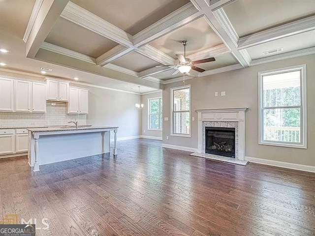 unfurnished living room with a healthy amount of sunlight, dark wood-style floors, ceiling fan, and a premium fireplace