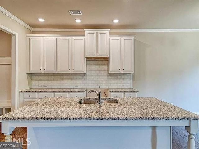 kitchen with white cabinetry, visible vents, light stone counters, and a sink