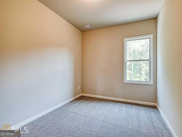 unfurnished room with carpet floors, visible vents, and baseboards