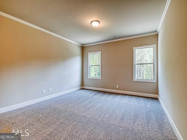 empty room featuring carpet, visible vents, baseboards, and ornamental molding