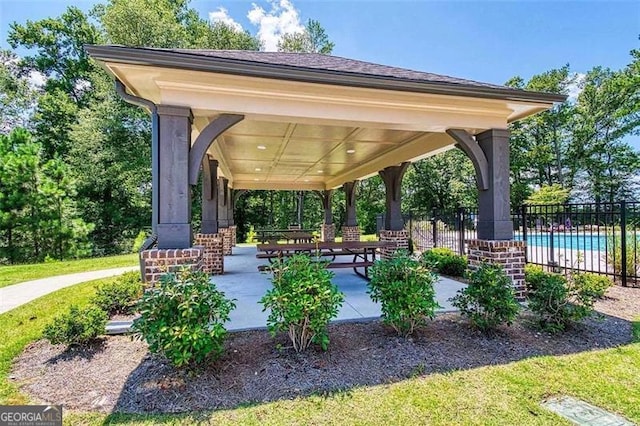 surrounding community with a swimming pool, fence, a patio, and a gazebo