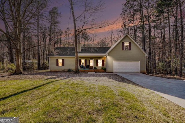 view of front of property with covered porch, concrete driveway, a lawn, and a garage