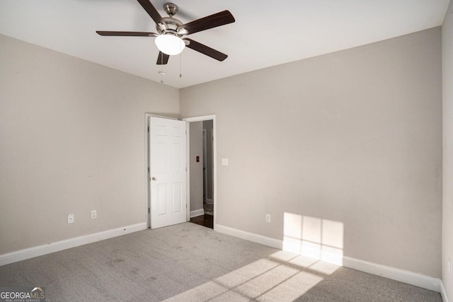 carpeted spare room with baseboards and a ceiling fan