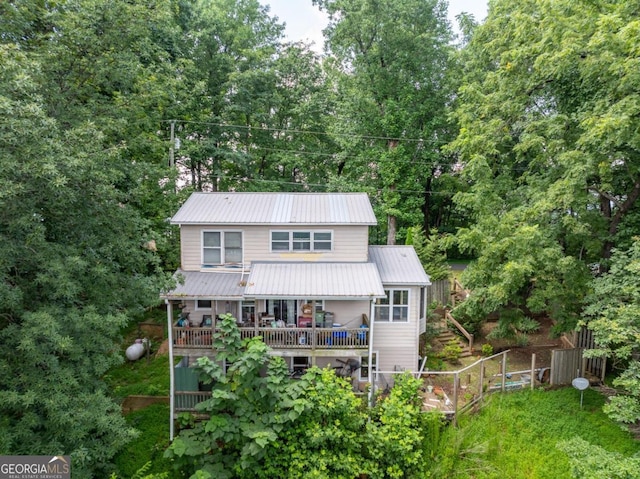 rear view of property with fence, metal roof, and a wooden deck