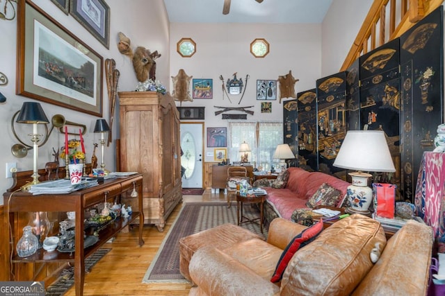 living room with light wood-style flooring, a high ceiling, and a ceiling fan