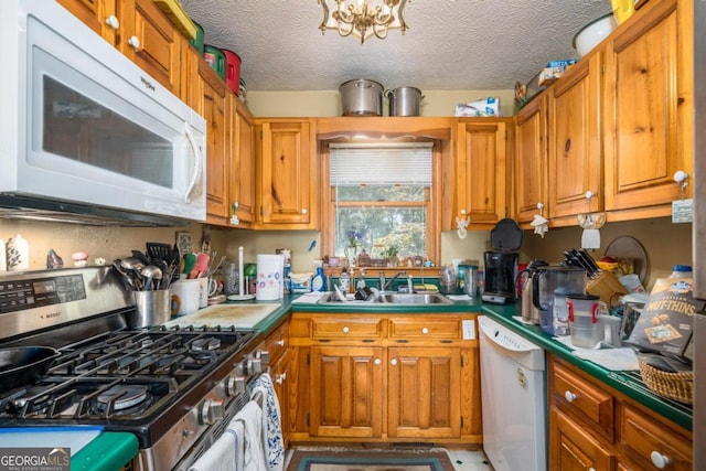 kitchen with brown cabinetry, white appliances, a sink, and a textured ceiling