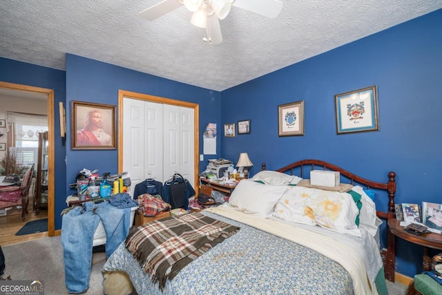 bedroom with a textured ceiling, ceiling fan, a closet, and carpet