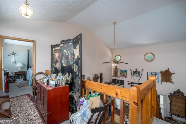 interior space with carpet floors, vaulted ceiling, a textured ceiling, and a ceiling fan