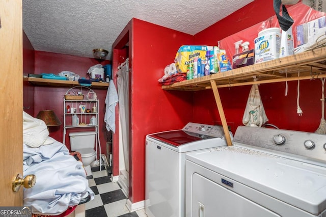 washroom with a textured ceiling, light floors, washing machine and clothes dryer, and laundry area