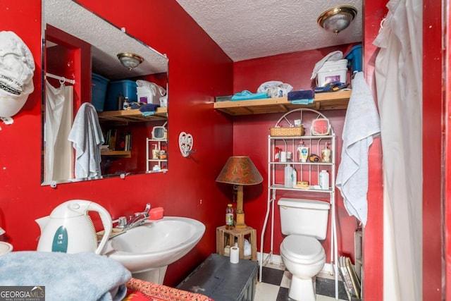 bathroom with a textured ceiling, toilet, and tile patterned floors