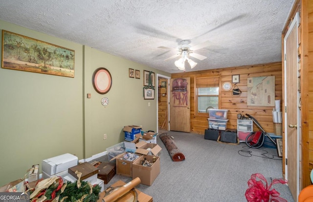 interior space with a textured ceiling, ceiling fan, and carpet flooring