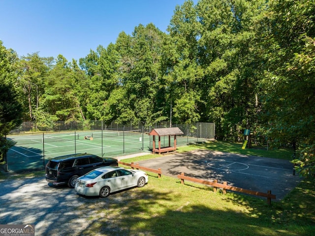 exterior space featuring a tennis court and fence