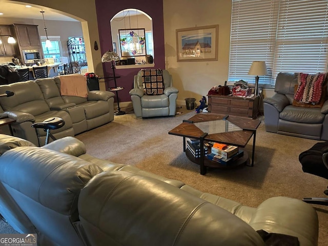 living room with arched walkways, carpet, and baseboards