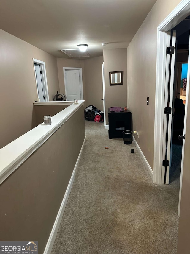 hall featuring baseboards, an upstairs landing, attic access, and light colored carpet