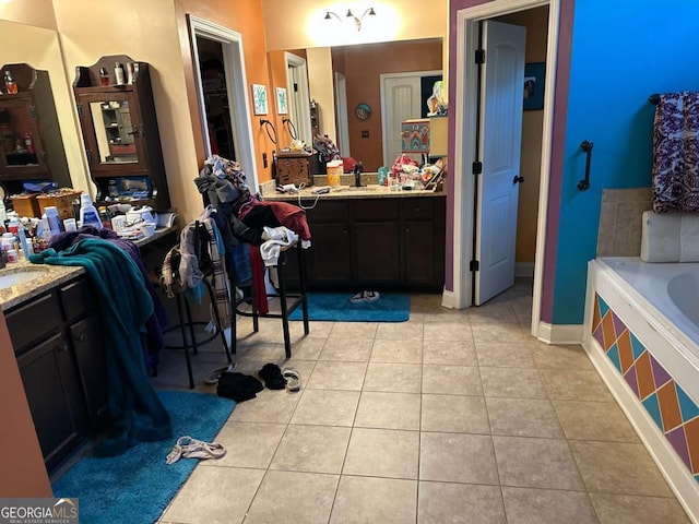 bathroom with a relaxing tiled tub, tile patterned flooring, baseboards, and vanity