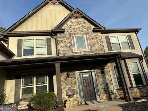 craftsman-style home featuring board and batten siding, stone siding, and covered porch