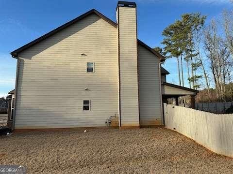 view of side of property with fence and a chimney