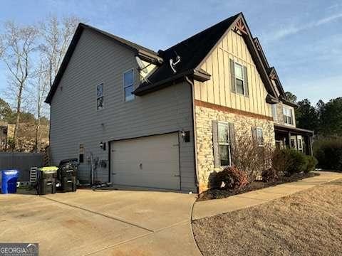 view of side of home featuring board and batten siding, concrete driveway, and an attached garage