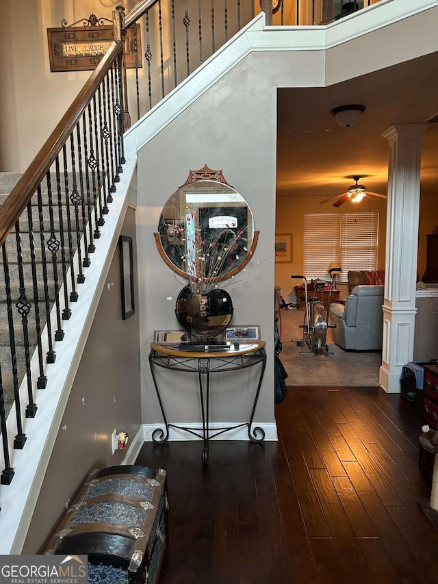 interior space featuring dark wood-type flooring, a high ceiling, ornate columns, and stairs