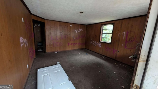 unfurnished room with crown molding, wooden walls, and a textured ceiling