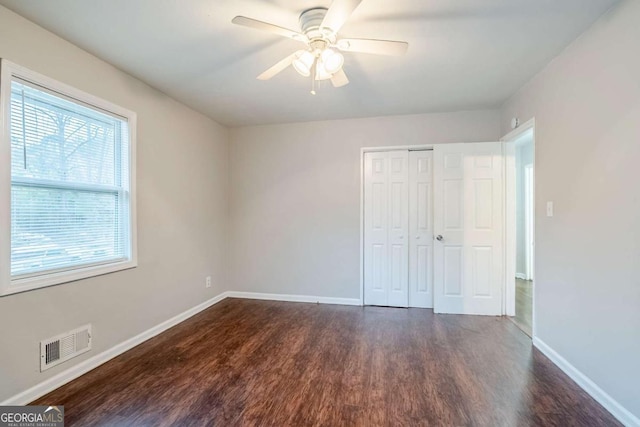 unfurnished bedroom featuring baseboards, visible vents, a ceiling fan, dark wood-type flooring, and a closet