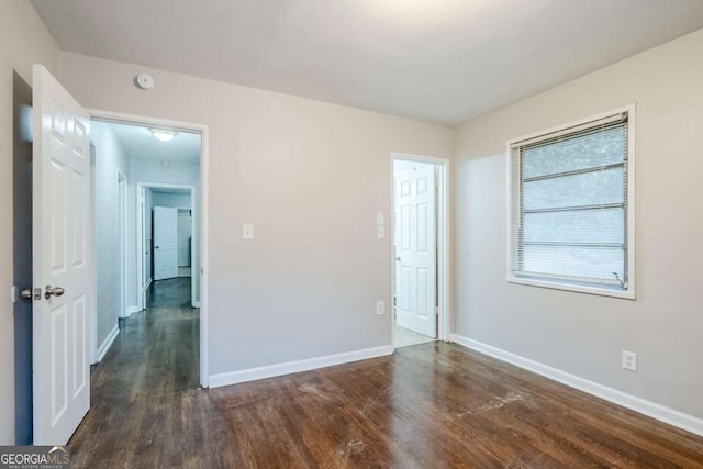 empty room with dark wood-type flooring and baseboards