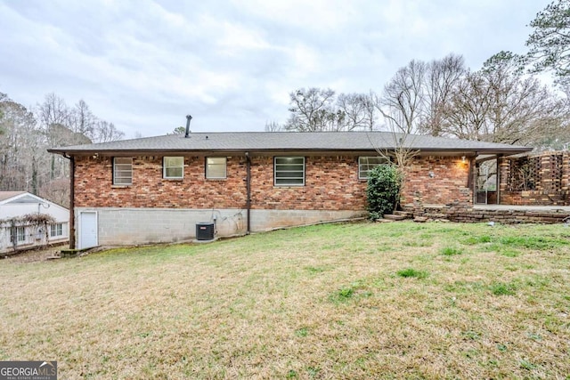 rear view of house featuring central air condition unit, a lawn, and brick siding